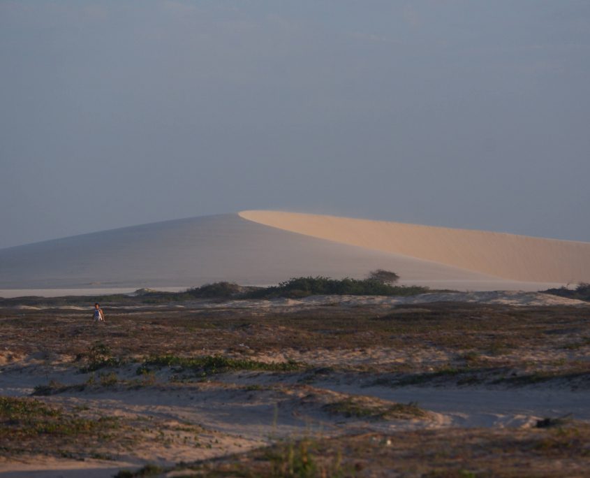 Dunas móveis de Jericoacoara com vegetação e o sol refletindo nas dunas