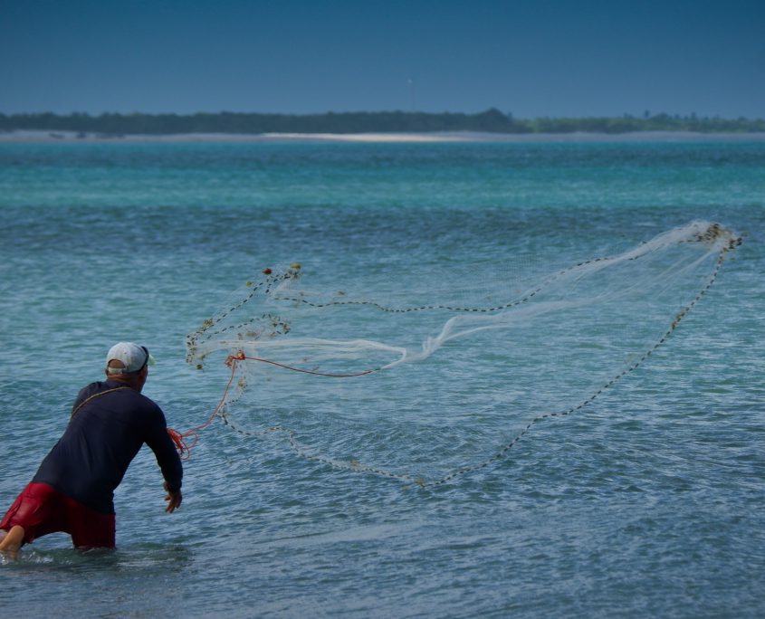 Pescador lançando a rede na praia de Jericoacoara, mas com várias cores de azul.